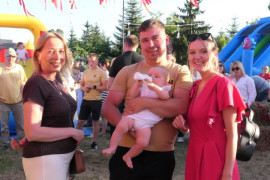 Dwie kobiety i mężczyzna stoją obok siebie. Mężczyzna trzyma na ręku małe dziecko 