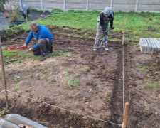 Dwaj mężczyźni przygotowują teren pod budowę paleniska  