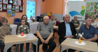 Kobity, mężczyźni i dzieci. Wszyscy siedzą na krzesłach. Uczestnicy spotkania literackiego