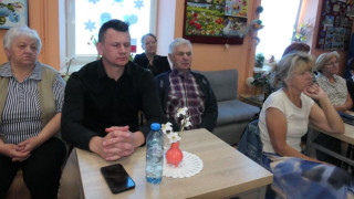 Kobiety i mężczyźni siedzą przy stolikach. Uczestnicy spotkania literackiego 