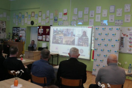Osoby siedzą na krzesłach. Uczestniczą w literackim spotkaniu online 