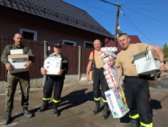 Czterech mężczyzn - strażacy - podczas akcji polegającej na niesieniu pomocy powodzianom 