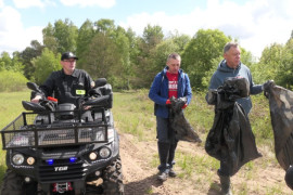 Dwaj mężczyźni idą obok siebie. Obok nich jedzie quadem mężczyzna