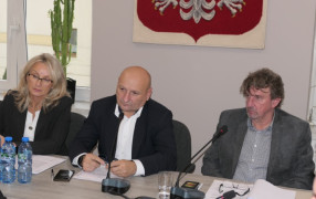 Kobieta i dwaj mężczyźni siedzą obok siebie. Wszyscy przysłuchują się rozmowie 