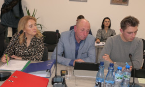 Kobieta i dwaj mężczyźni siedzą obok siebie. Wszyscy przysłuchują się rozmowie 