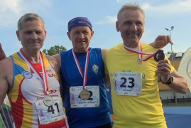 Trzej mężczyźni w sportowych strojach stoją obok siebie. Wszyscy mają medale 