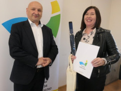 Kobieta i mężczyzna stoją obok siebie. Kobieta trzyma w ręku dyplom 