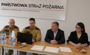 Kobieta i trzej mężczyźni siedzą przy stole. Członkowie jury konkursu wiedzy pożarniczej 