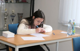 Dziewczynka siedzi przy stoliku. Rozwiązuje test z wiedzy przeciwpożarowej 