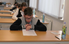 Chłopiec siedzi przy stoliku. Rozwiązuje test z wiedzy przeciwpożarowej 