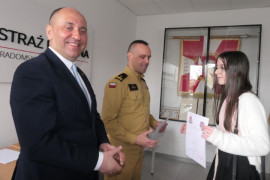 Dwaj mężczyźni i dziewczynka. Dziewczynka trzyma w ręku dyplom 