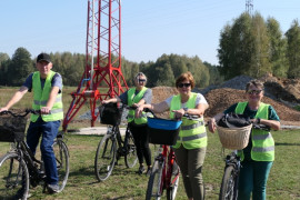 Grupa osób w kamizelkach odblaskowych stoi przy rowerach 