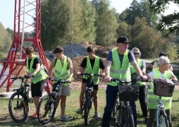 Grupa osób w kamizelkach odblaskowych stojąca przy rowerach 