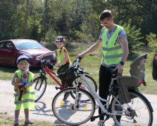 Mężczyzna i małe dziecko w odblaskowych kamizelkach. Oboje stoją przy rowerze