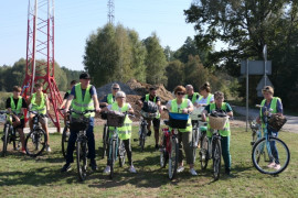 Grupa osób w odblaskowych kamizelkach stoi przy rowerach 