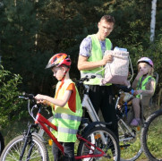 Dorośli i dzieci w kamizelkach odblaskowych - uczestnicy rajdu rowerowego 