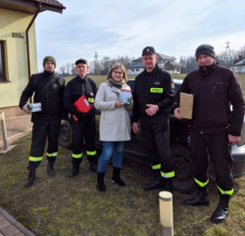 Kobieta i czterej druhowie. Osoby znajdują się przed domem  
