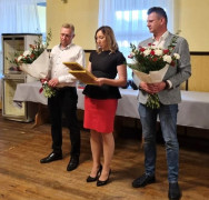 Kobieta i dwóch mężczyzn. Mężczyźni trzymają w ręku kwiaty