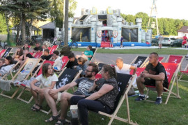 Osoby siedzą na leżakach 