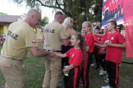 Moment gratulacji. Starsi strażacy gratulują młodzieży 