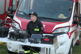 Wóz strażacki. Przed wozem siedzi strażak 