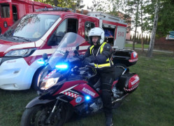 Wóz i motocykl strażacki. Na motorze siedzi strażak. 