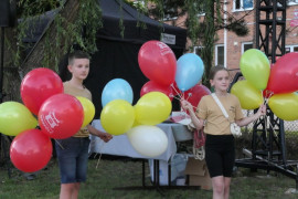 Dziewczynka i chłopiec trzymają w dłoniach balony 