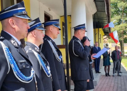Druhowie w oficjalnych mundurach stoją przez strażnicą. Jeden z druhów przemawia 