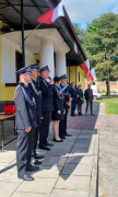 Druhowie w mundurach stoją przed strażnicą 