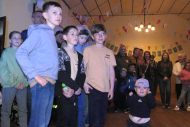 Grupa osób stojących obok siebie. Na pierwszym planie młodzi chłopcy i małe dziecko 
