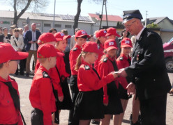 Strażak wręcza legitymacje członkowskie młodym strażakom 