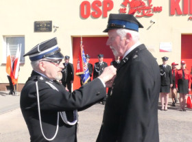 Strażak wręcza medal zasłużonemu druhowi 