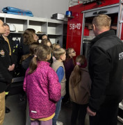 Dzieci w towarzystwie osoby dorosłej oglądają bojowy wóz strażacki 