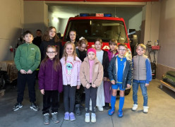 Grupa dzieci: dziewczynki i chłopcy stoją obok strażackiego wozu bojowego