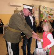 Dwaj mężczyźni wręczają nagrody dziewczynce. 