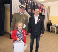 Dwaj mężczyźni i dziewczynka. Dziewczynka trzyma w ręku dyplom. 