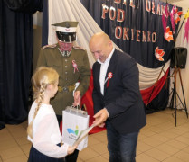 Dwaj mężczyźni wręczają dziewczynce nagrody. 