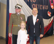 Dwaj mężczyźni i dziewczynka. Dziewczynka trzyma w ręku dyplom. 