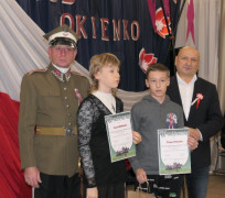 Dwaj mężczyźni stoją obok dziewczyny i chłopca. Młodzież trzyma w ręku dyplomy