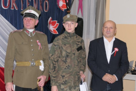 Dwaj mężczyźni i chłopiec. Chłopiec trzyma w ręku dyplom 