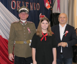 Dwaj mężczyźni i dziewczynka. Dziewczyna trzyma w ręku dyplom 