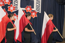 Trzy dziewczynki trzymające na ramieniu flagi