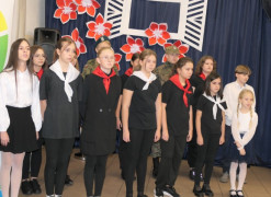 Grupa dzieci stojąca obok siebie. Dzieci mają na sobie apaszki koloru białego i czerwonego