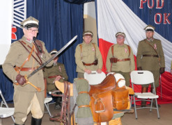 Czterej mężczyźni w mundurach. Jeden z nich trzyma w dłoni szablę 