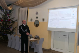 Mężczyzna w mundurze strażaka stoiki przed rzutnikiem 