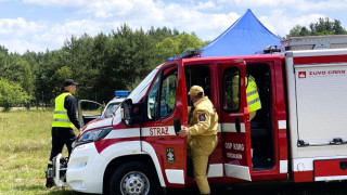 Samochód strażacki. Obok samochodu znajduje się trzech strażaków 