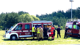 Samochód strażacki. Obok Samochodu znajdują się osoby w mundurach: straż i policja 