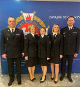 Trzy panie i dwóch panów. Osoby ubrane są w mundury strażackie. Osoby stoją obok siebie