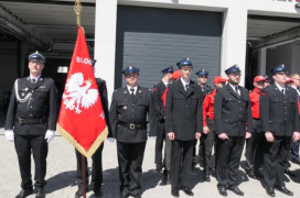Strażacy stoją w dwuszeregu przed strażnicą 
