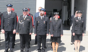 Strażacy stoją w dwuszeregu przed strażnicą 